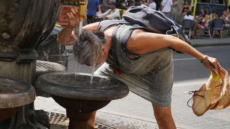 Una mujer se refresca en una fuente en Madrid. (Foto NA/Reuters).